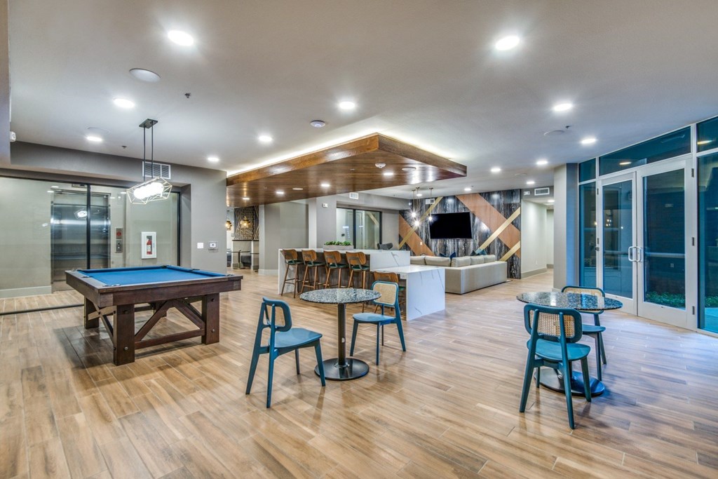 A room with a pool table and chairs.
