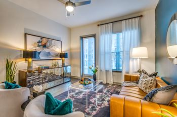 A living room with a white sofa, a glass coffee table, and a painting on the wall.