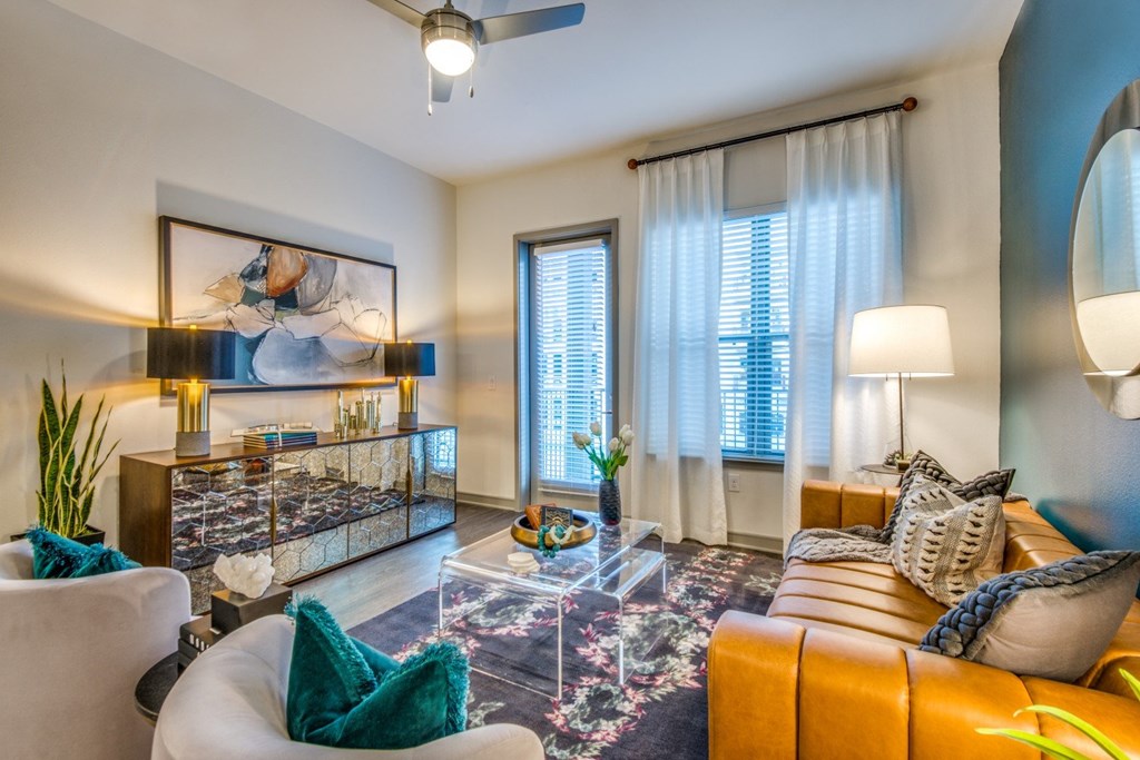 A living room with a white sofa, a glass coffee table, and a painting on the wall.