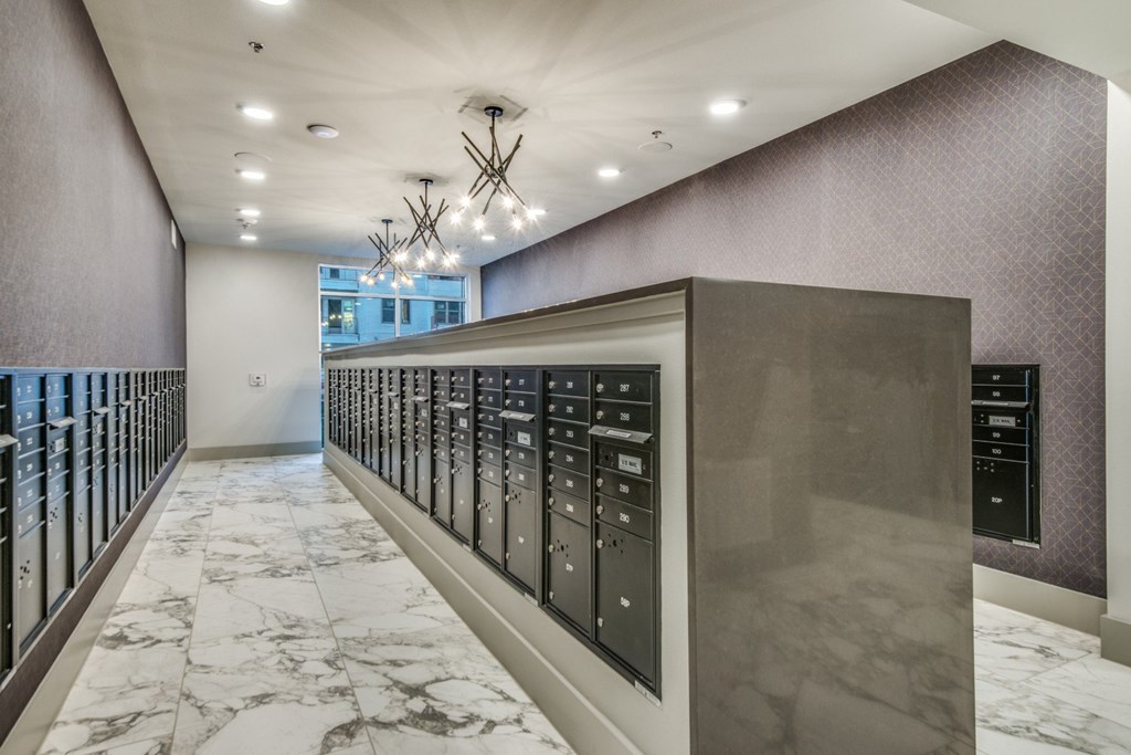 A long hallway with a marble floor and a wall of elevators.