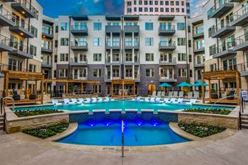 A large swimming pool surrounded by a stone wall and lounge chairs.