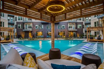 A large outdoor pool area with a wooden pergola and lounge chairs.