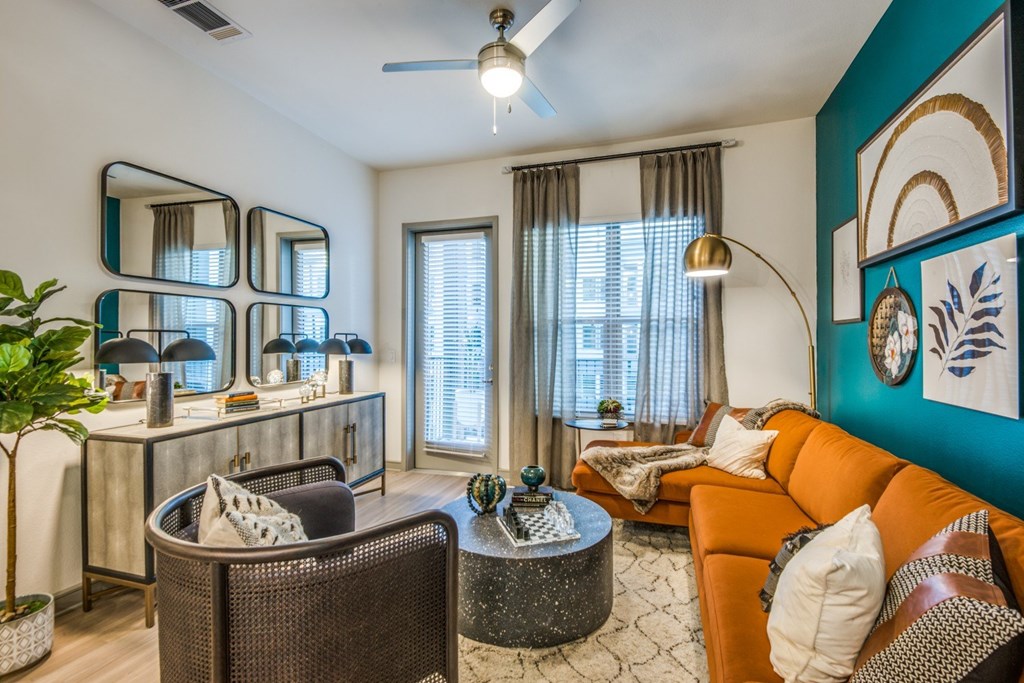 A living room with a brown chair, a round table, and a mirror on the wall.