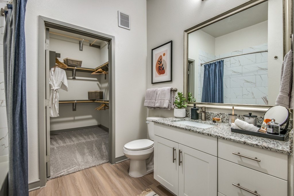 A bathroom with a toilet, sink, and mirror.