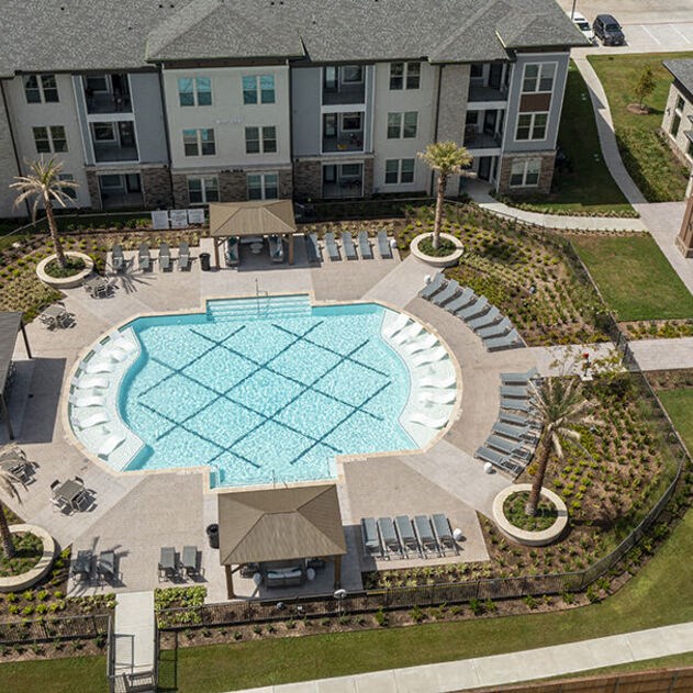 an aerial view of an oval swimming pool in an apartment complex