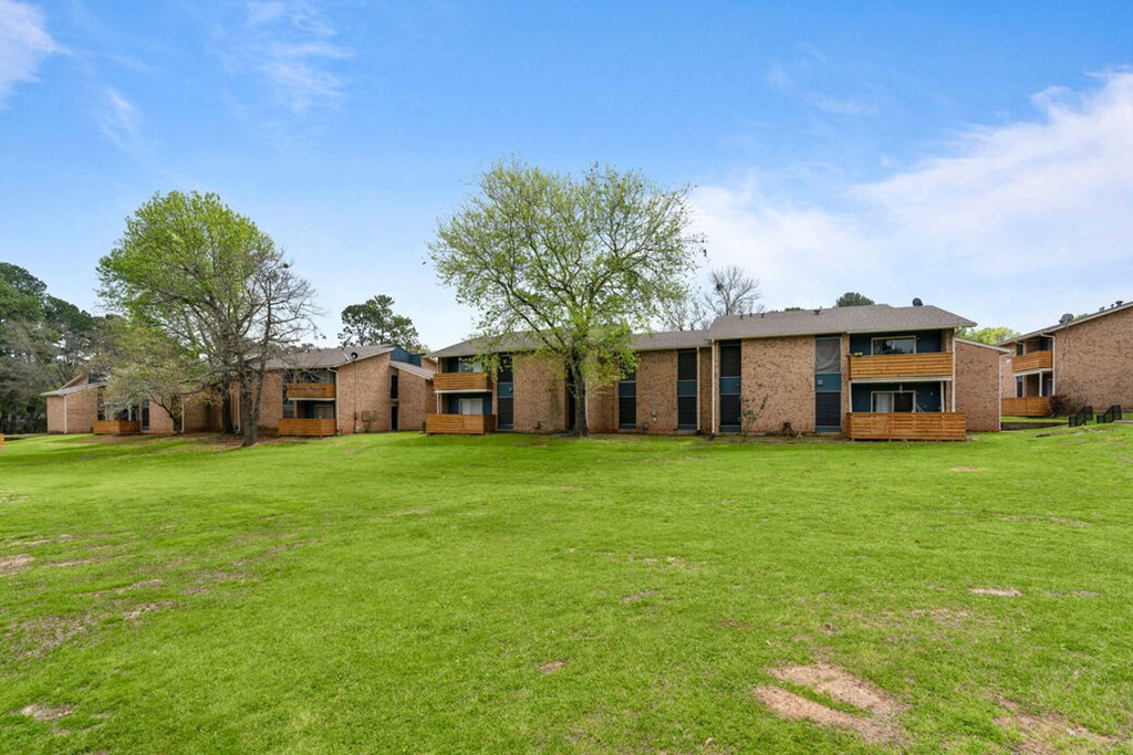 a view of a building with a grass field and trees