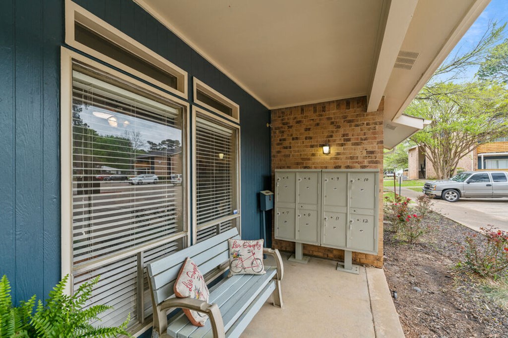 the front porch of a house with a bench and mailboxes
