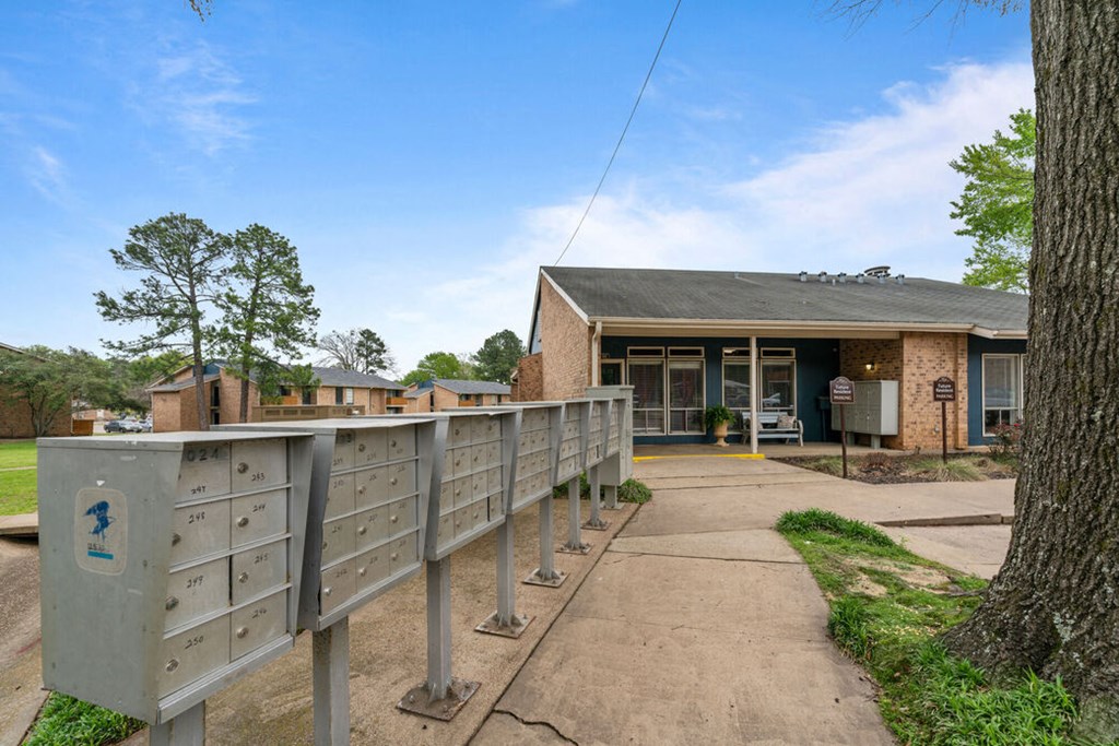 the front of a building with a fence with mailboxes