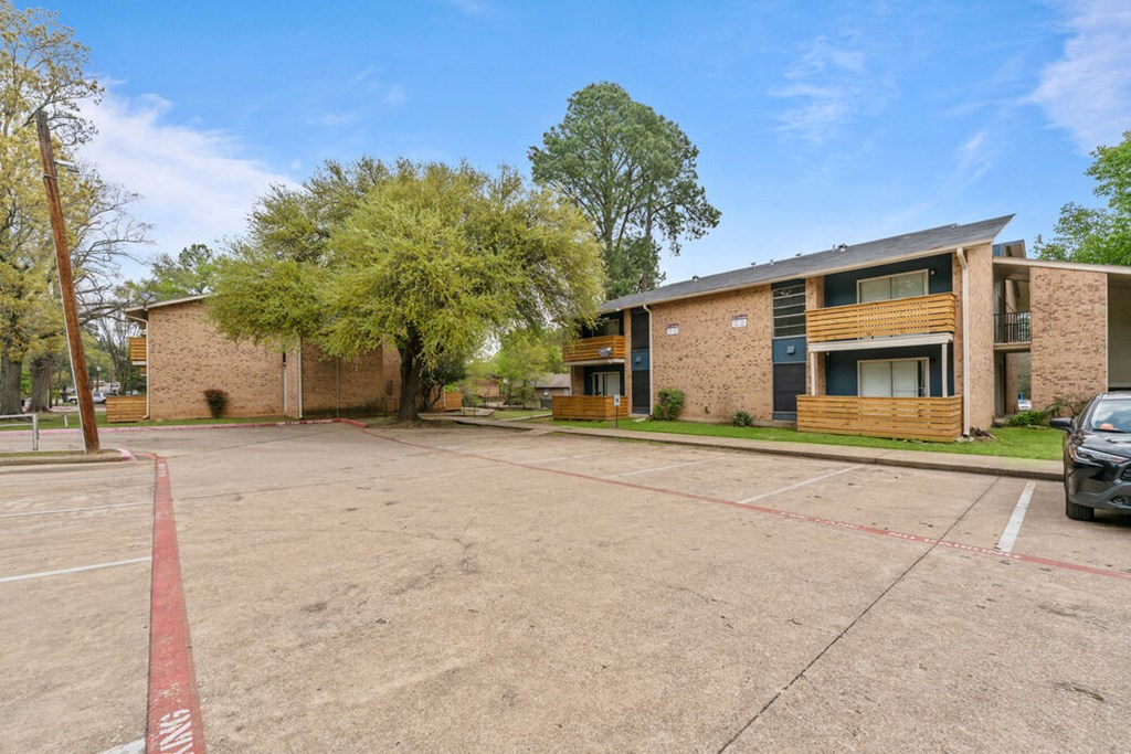 an empty parking lot in front of a brick apartment building
