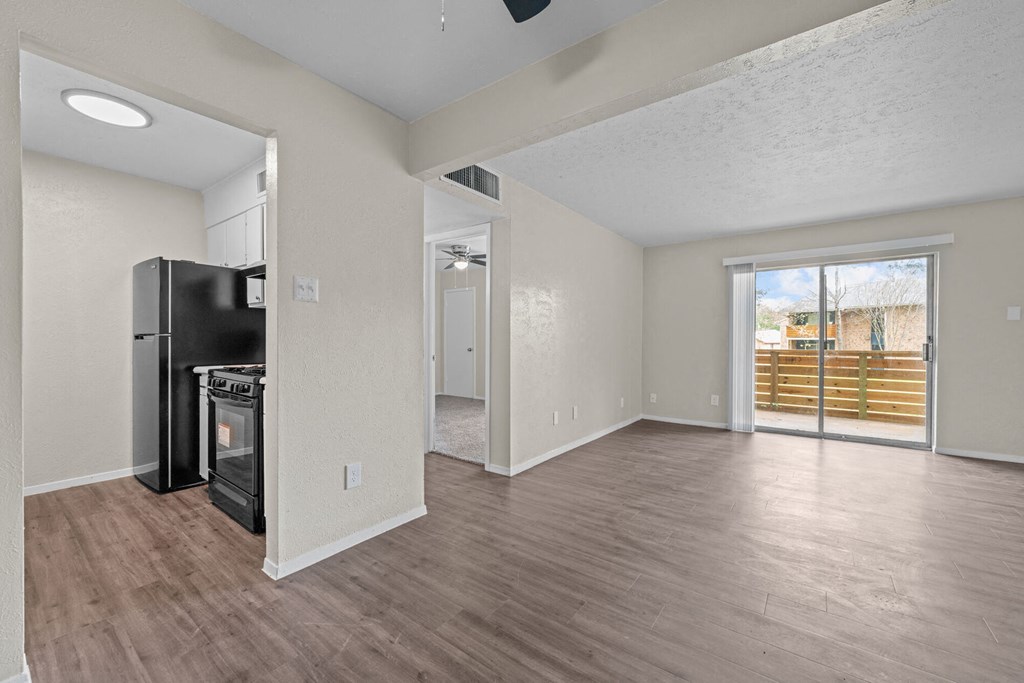 a spacious living room with a kitchen and a door to a patio