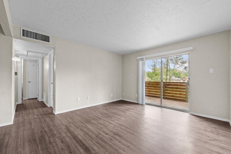 an empty living room with a sliding glass door to a patio