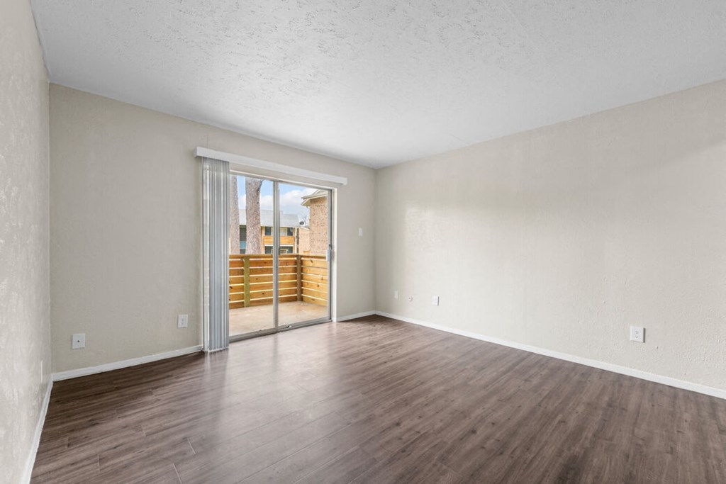 an empty living room with a sliding glass door to a patio
