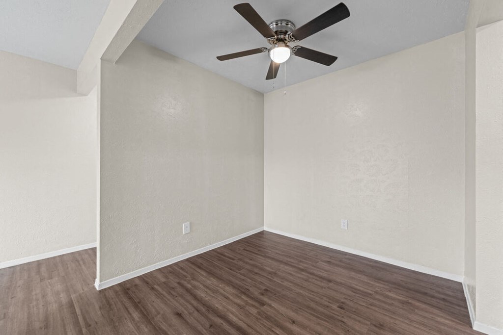 an empty living room with a ceiling fan and wood floors