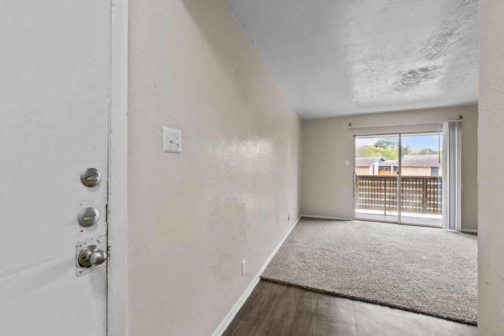 an empty living room with a door to a balcony