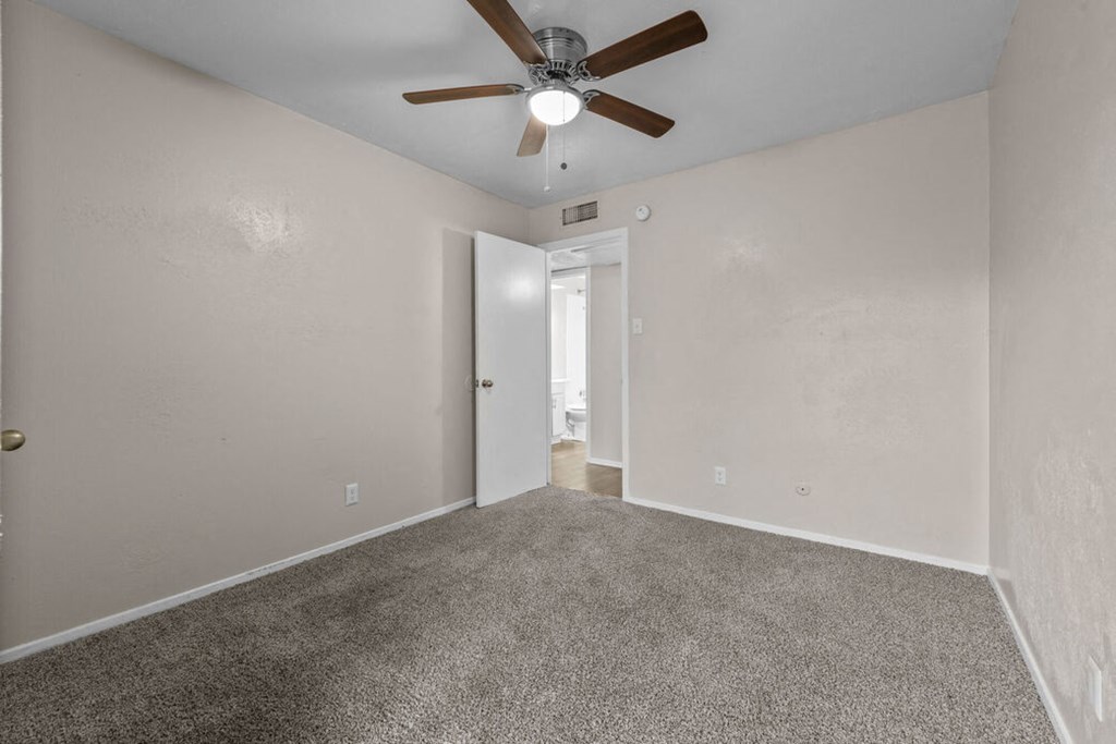 an empty living room with a ceiling fan and carpet