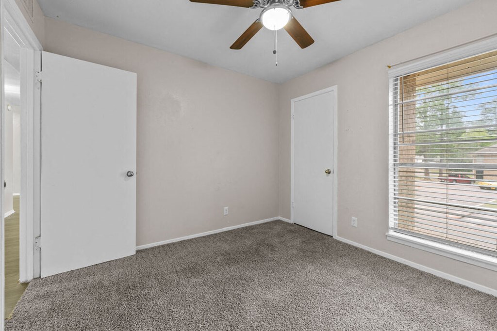 a bedroom with a large window and a ceiling fan
