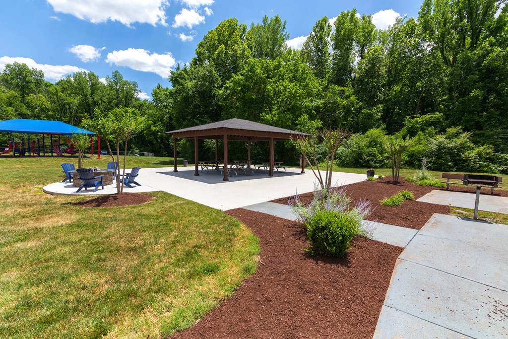 a picnic area with benches and a pavilion in the middle of a grassy area