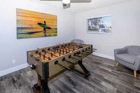 a foosball table in a living room with a chair and a painting