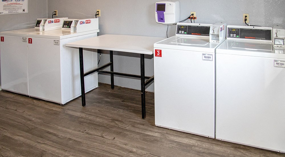 a laundry room with four washing machines and a table