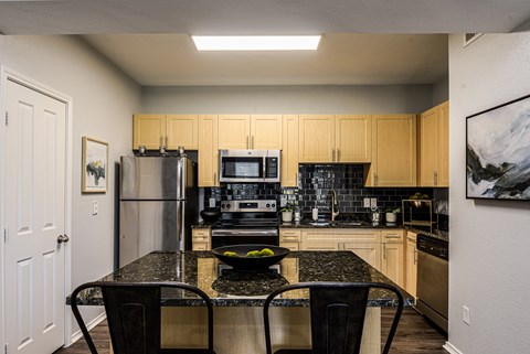 A kitchen with a table and chairs in the middle.