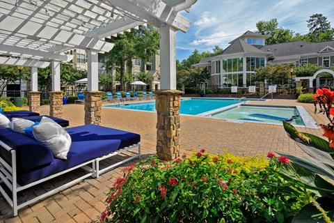 A pool area with sun loungers and a white pergola.