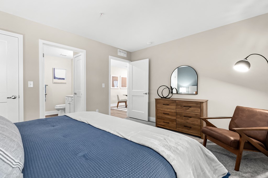 a bedroom with a bed and a dresser and a bathroom