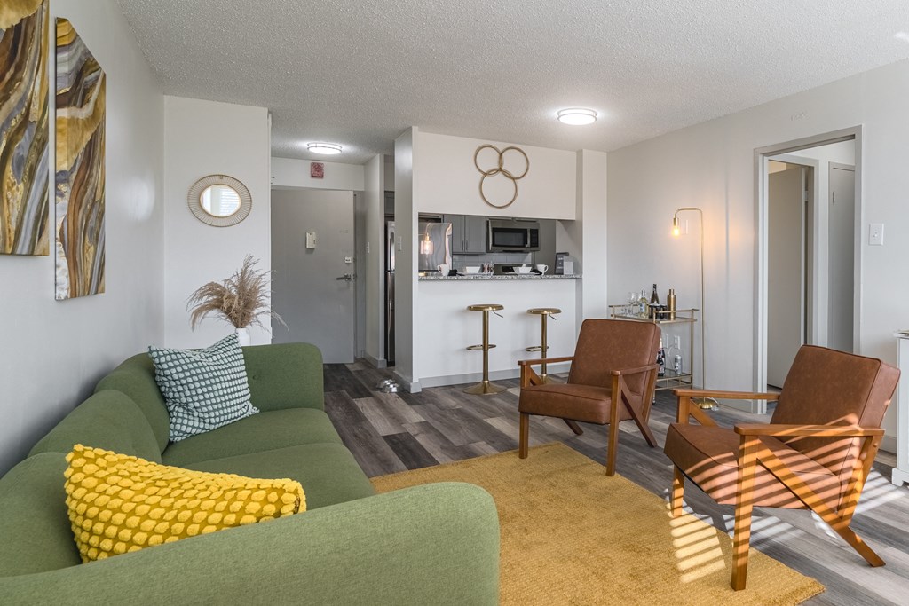 a living room with a couch and two chairs and a kitchen