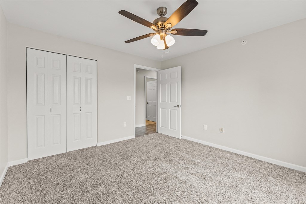an empty living room with a ceiling fan and white doors