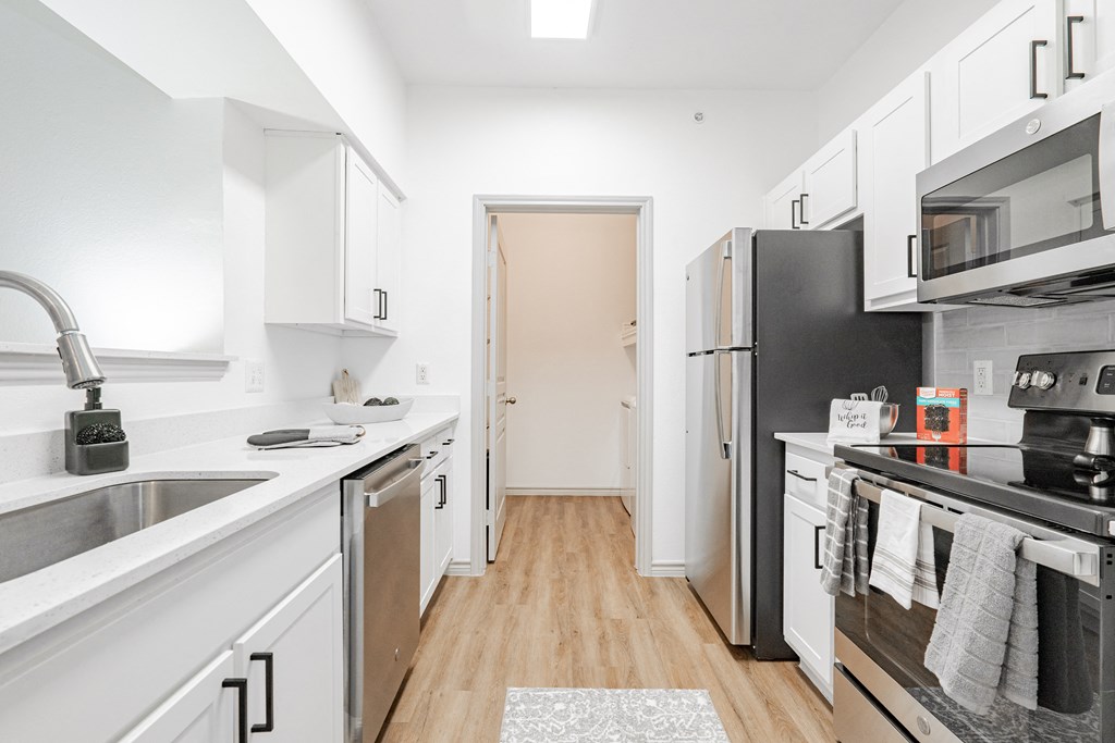 a renovated kitchen with white cabinets and stainless steel appliances