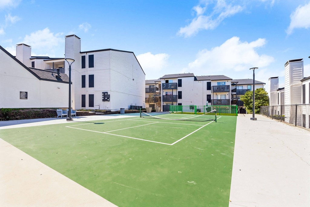 a tennis court with apartments in the background