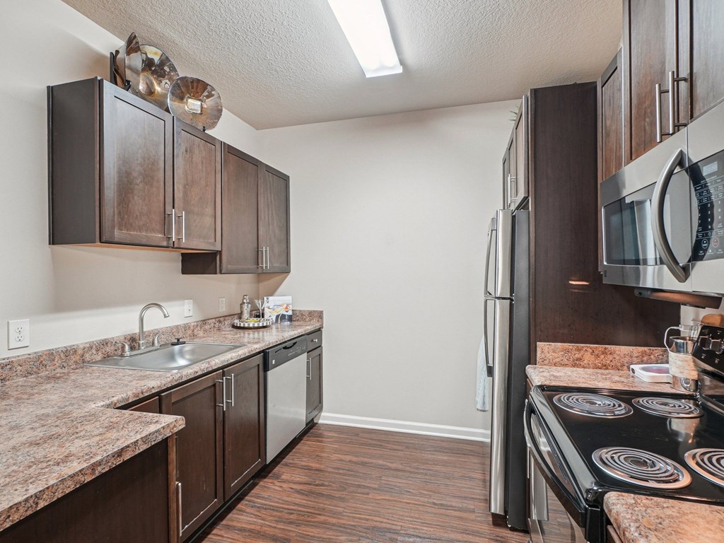 A kitchen with dark wood cabinets and a granite countertop.