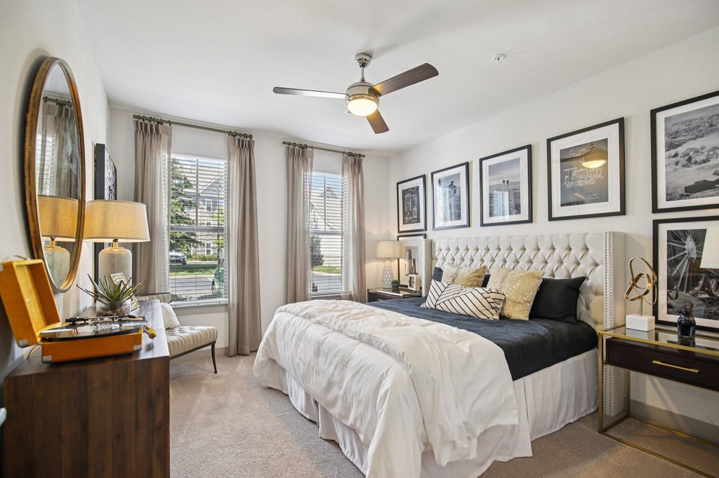 A bedroom with a large bed, a mirror, and a ceiling fan.