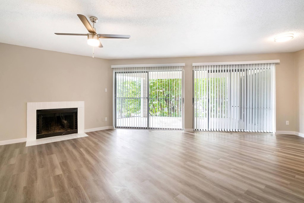 an empty living room with a fireplace and sliding glass doors
