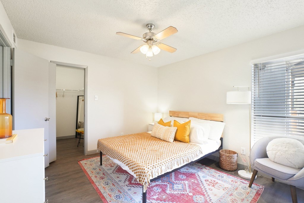 A bedroom with a bed, chair, and rug.