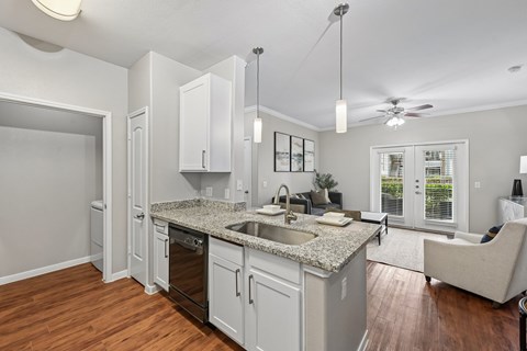 A kitchen with white cabinets and a granite countertop.