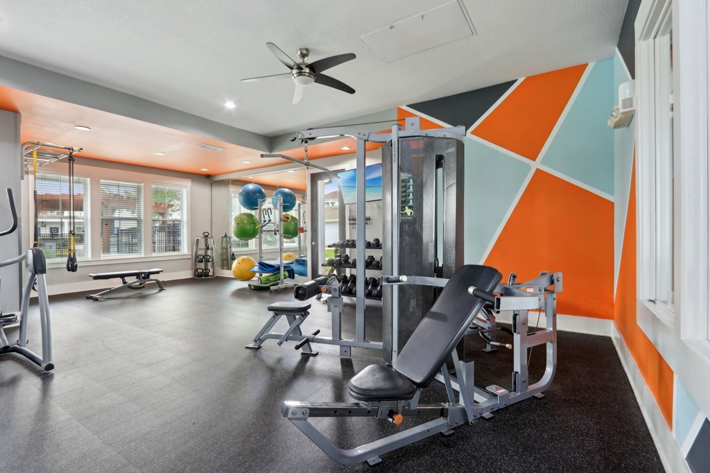 A gym with orange and blue walls and a variety of equipment.