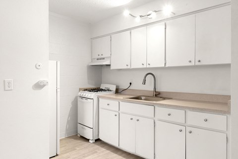 a kitchen with white cabinets and a sink and a stove