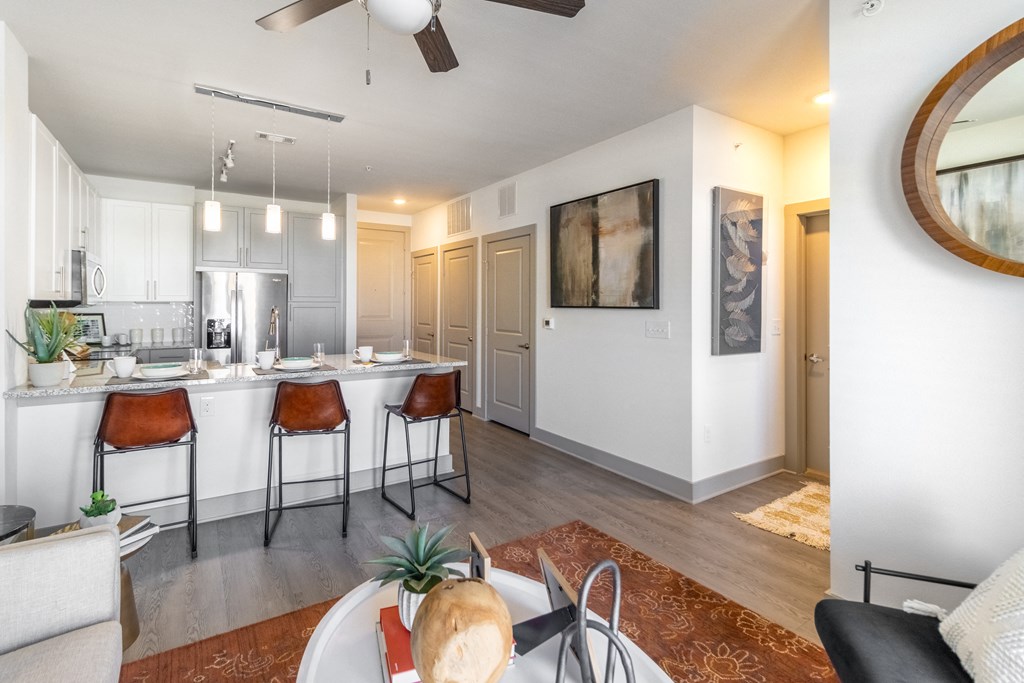 a living room and kitchen area with white walls and a ceiling fan