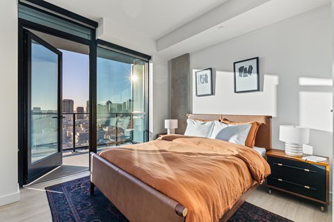 A bedroom with a large bed and a view of the city through the window.