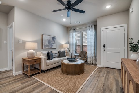 A living room with a white couch, a round coffee table, and a ceiling fan.