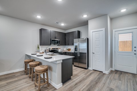 A kitchen with a white countertop and wooden bar stools.