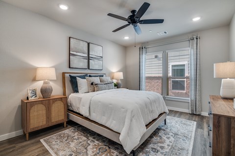 A bedroom with a bed, nightstands, and a ceiling fan.