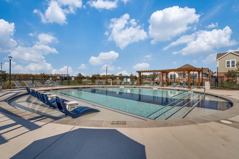 A large outdoor swimming pool with a slide and a gazebo in the background.
