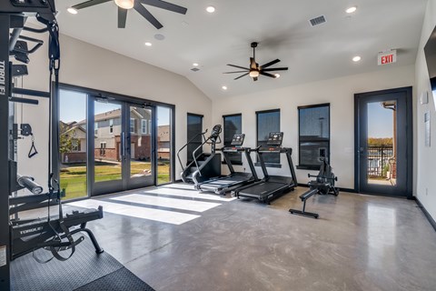 A spacious home gym with a treadmill, elliptical machines, and a weight bench.