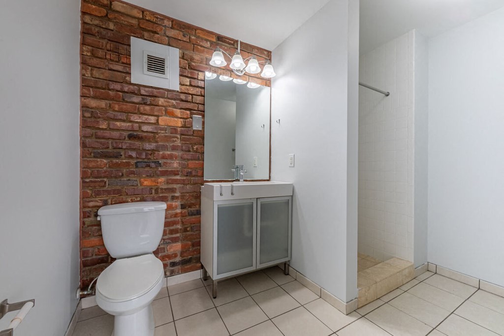 a bathroom with a brick wall and a toilet and a sink