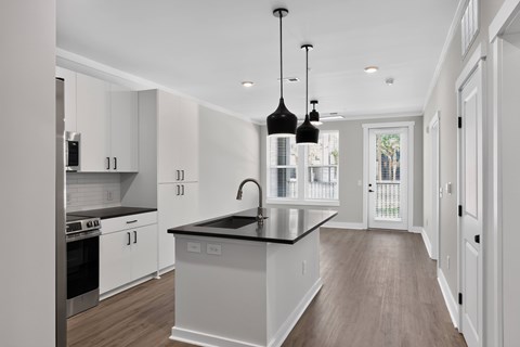 A modern kitchen with white cabinets and a black countertop.