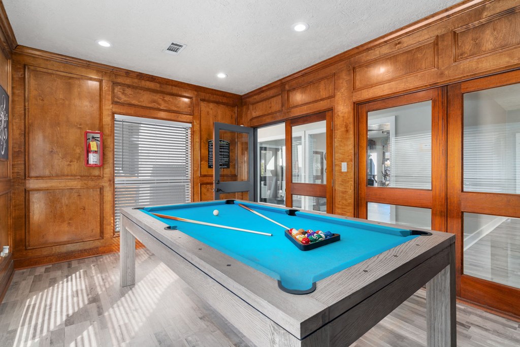 a pool room with a blue pool table and wood walls