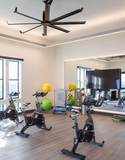 a workout room with exercise bikes and a tv