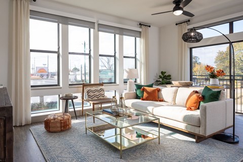 A living room with a white couch, a glass coffee table, and a ceiling fan.