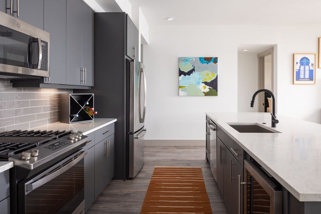 a kitchen with gray cabinets and white countertops and a stainless steel refrigerator